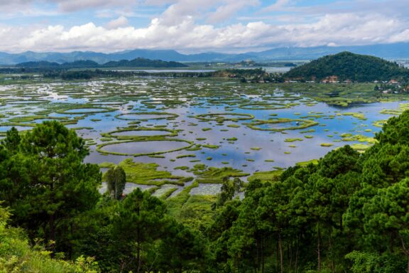 Green hills and Loktak Lake sit under a cloudy sky.