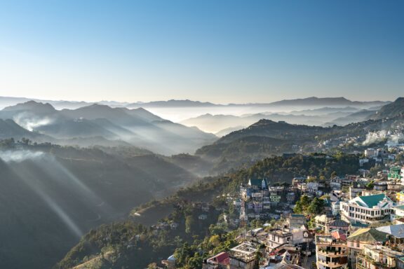 An aerial view of Aizawl city, surrounded by cloud-covered hills.