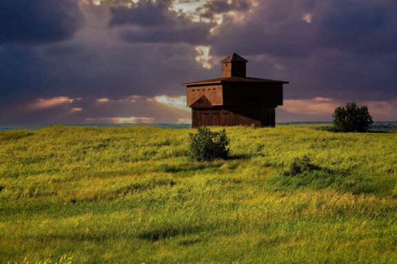 A wooden fort is backed by storm clouds in Fort Abraham Lincoln State Park in Morton County, North Dakota.