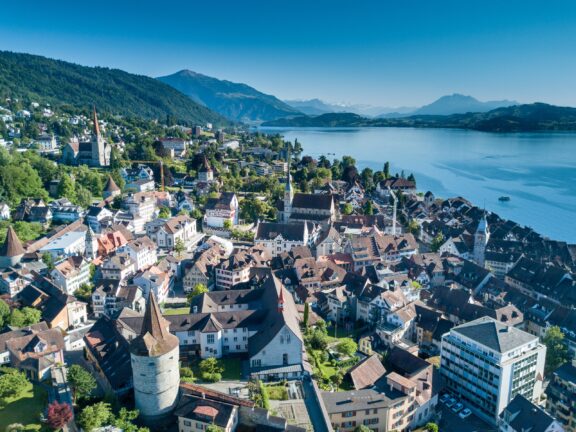 An aerial view of Zug, Switzerland with water and mountains in the background.