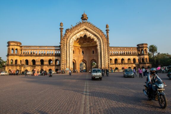 Cars, motorbikes, and people travel outside Rumi Darwaza, illuminated by the sun in Lucknow, India.