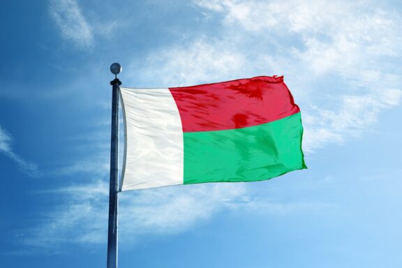 Flag of Madagascar waving against a blue sky.