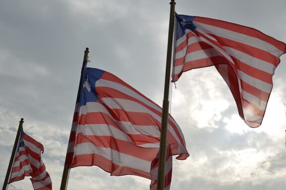 Several Liberian flags fluttering in the wind against a cloudy sky.