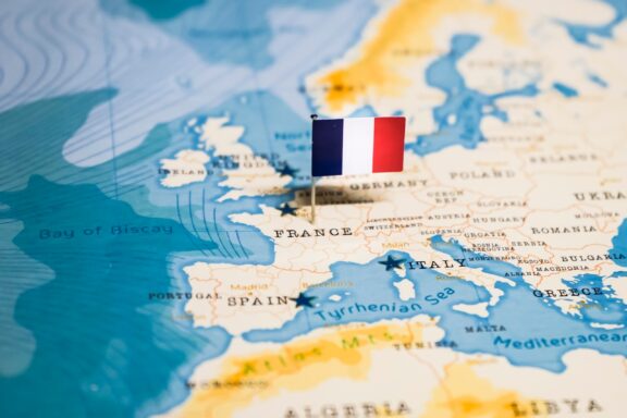 A pin with the French flag on a map highlighting France's location.