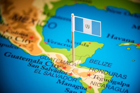 A close-up of a map showing Central America with a flag pin marking Guatemala.