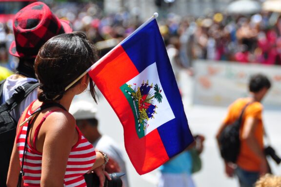 A person holding the Haitian flag at a crowded outdoor event.