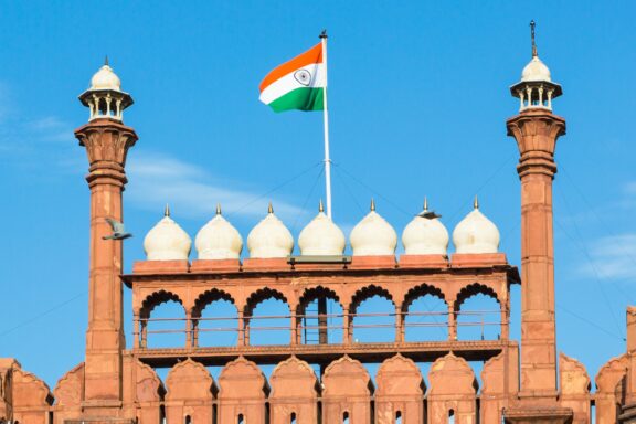 Indian flag waving above the Red Fort under a clear blue sky.