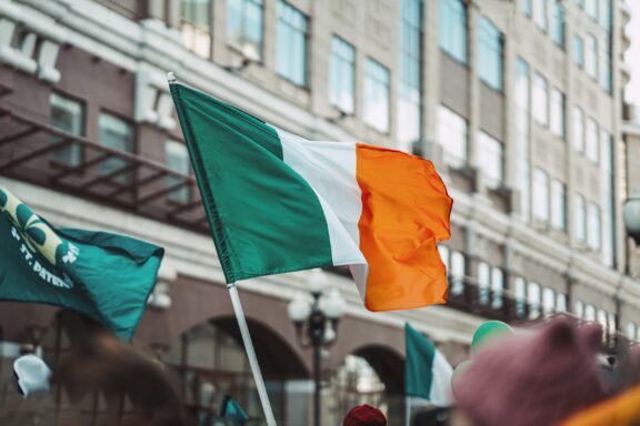 Irish flag waving with a blurred street scene in the background.