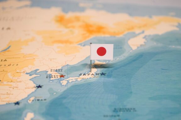 A pin with the flag of Japan placed on Tokyo on a world map.