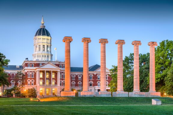 A low-angle view of the Columns landmark on the University of Missouri campus at sunset.