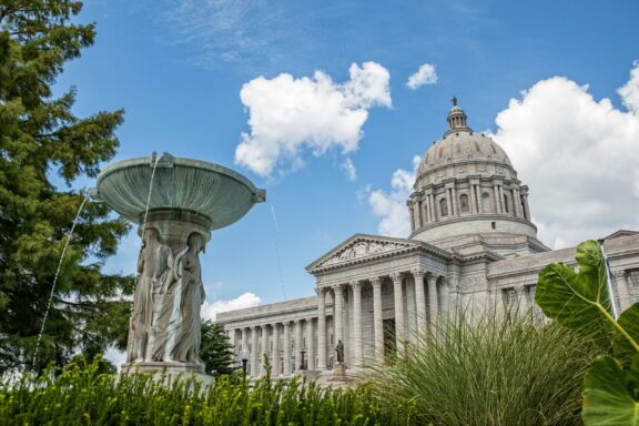 A low-angle view of a fountain and the front of the Missouri Capitol Building in Jefferson City.