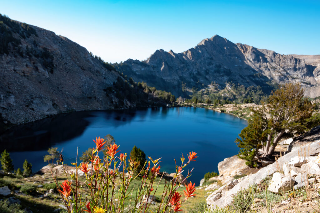 Liberty Lake sits between tall rock formations in the Ruby Mountains on a clear day.  