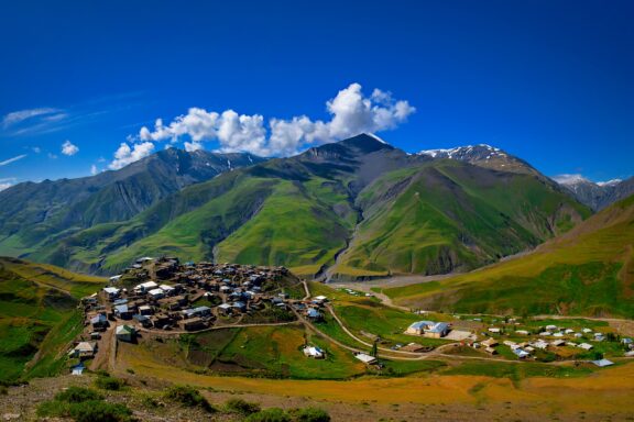 The village of Khinalug can be seen from a distance, backed by mountains on a clear day.