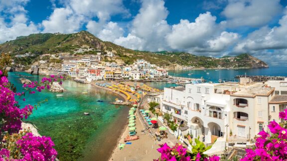 Beach tents line a strip of land bordered by beautiful water in Sant’Angelo, Ischia.