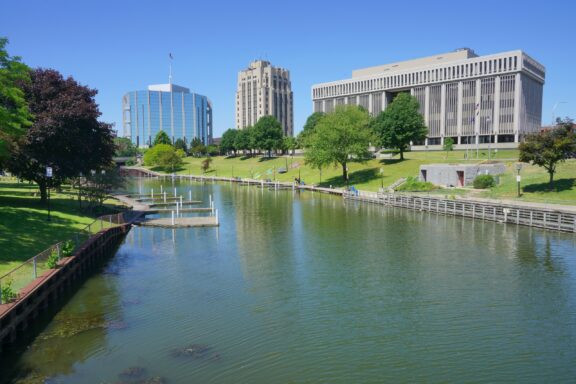 A view of a small waterway next to large buildings on a sunny day in Mount Clemens, Michigan.