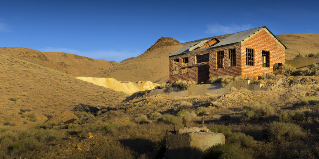 An abandoned brick building stands in the dusk light in a desert in Pershing County.