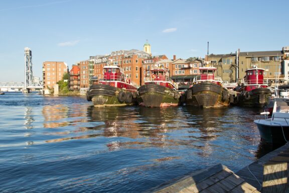 Four red boats sit in the water on a sunny day in Portsmouth, New Hampshire.