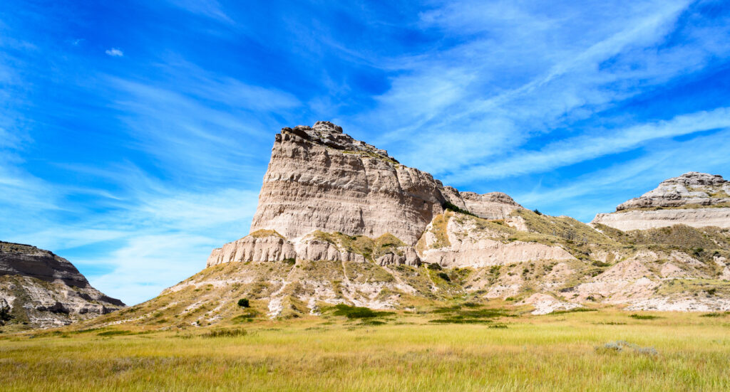 A towering rock formation emerges from grassy plains in Scottsbluff, Nebraska.