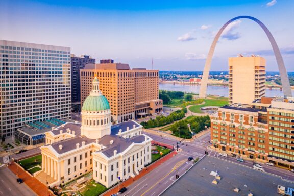 An aerial view of the courthouse and arch surrounded by tall buildings in downtown St. Louis, Missouri.