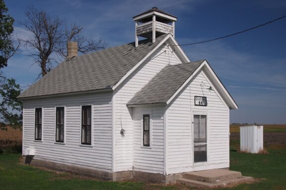 A small, white schoolhouse sits in a field in Traverse County, Minnesota.