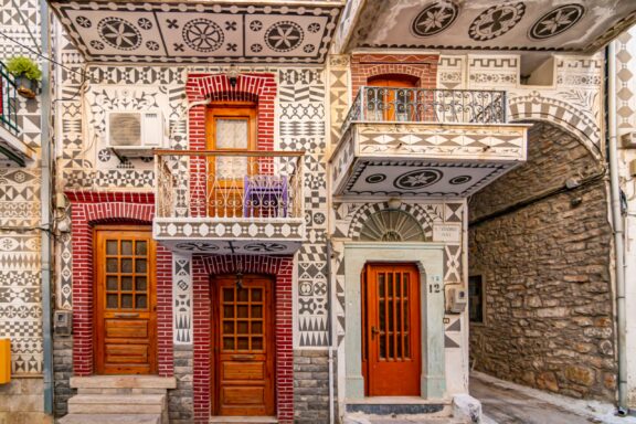 A ground-level view of buildings covered in geometric designs in the village of Pyrgi.