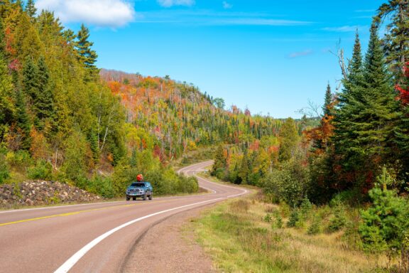 A car drives on a rural highway surrounded by beautiful natural scenery in Minnesota’s Cook County.