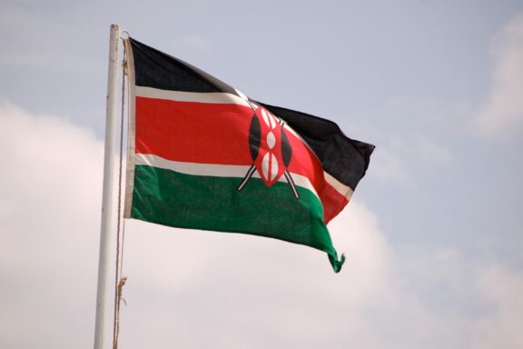 Flag of Kenya waving against a clear sky.