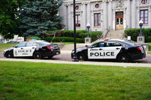 Police Cars Parked in Front of a Courthouse Building Two police vehicles are parked along the side of a street in Kenosha, Wisconsin, a "stop and identify" state.