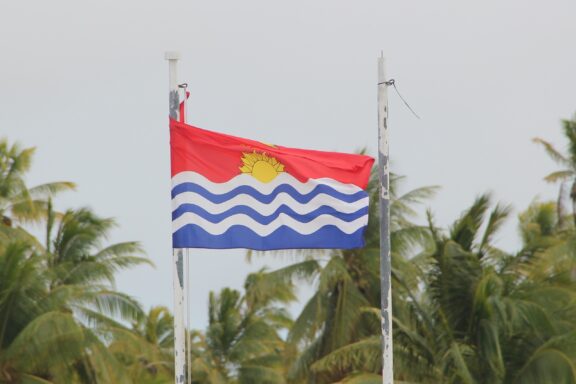 Flag of Kiribati waving with palm trees in the background.