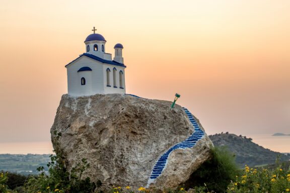 A small white church sits atop a rock in Kos, Greece.