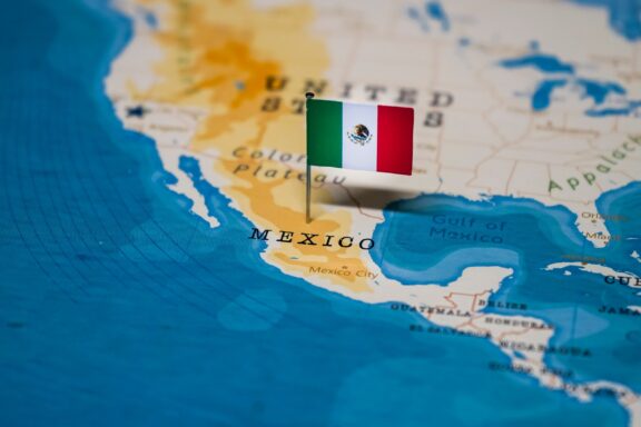 A close-up of a map showing Mexico's location with a Mexican flag pin.