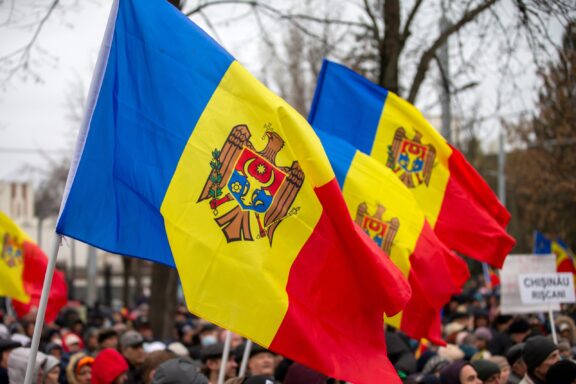 Moldovan flags waving at a gathering with people in the background.