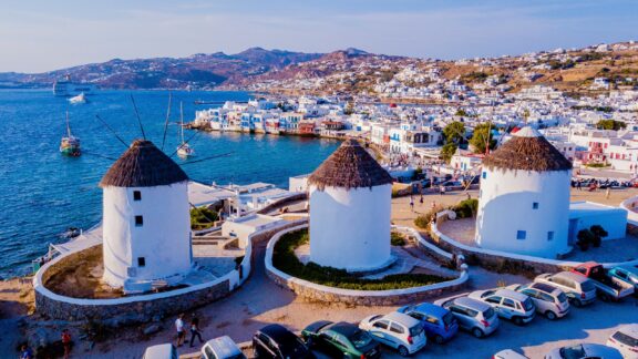 Three white windmills overlook the water in Mykonos.