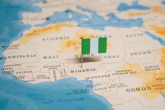 A pin with the flag of Nigeria placed on Nigeria's location on a world map.