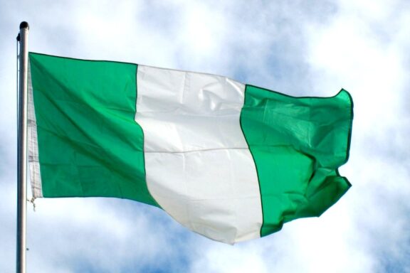 Nigerian flag waving against a clear sky.