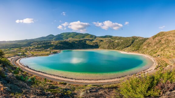 Green hills surround Venere Lake on a sunny day.