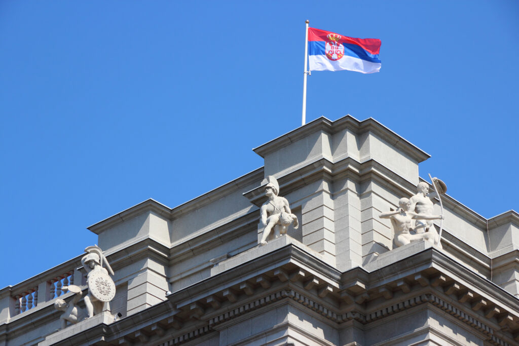 Serbian flag waving atop a building against a clear blue sky.