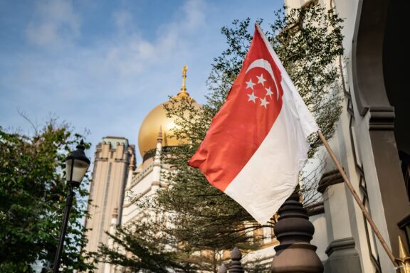 Singapore flag in the foreground with the Sultan Mosque's golden dome in the background.