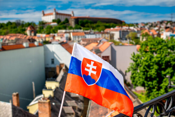 Slovak flag waving with the cityscape of Bratislava in the background.