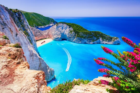 Navagio Beach can be seen in the distance surrounded by cliffs and bright blue waters on the island of Zakynthos.