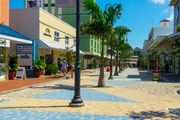 People walk down a colorful street in George Town on a sunny day.