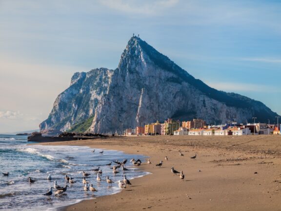 A view of the Rock of Gibraltar from a sandy beach.