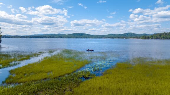 A view of Lake Pleasant from Speculator, New York under a blue sky.