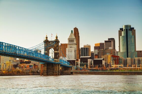 The Cincinnati skyline stands next to the water on a clear day.