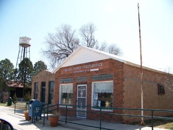 A street-level view of the brick façade of the Mosquero post office.