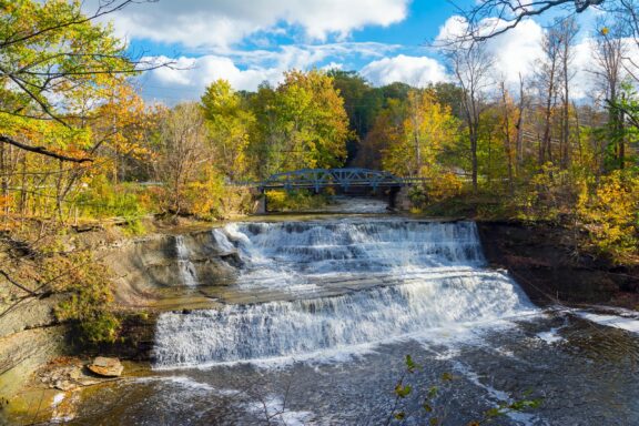 Trees with green and golden leaves line small waterfalls in Ohio’s Lake County.