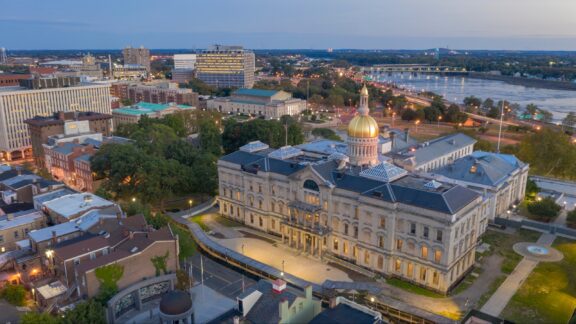 An aerial view of the New Jersey State House with the Delaware River in the background.