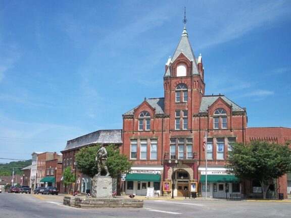 A street-level view of a sculpture and a large brick building in downtown McConnelsville.