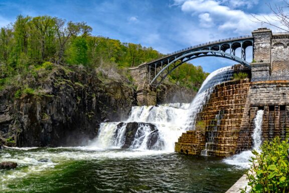 A low-angle view of a bridge spanning a waterfall in Westchester County, New York.