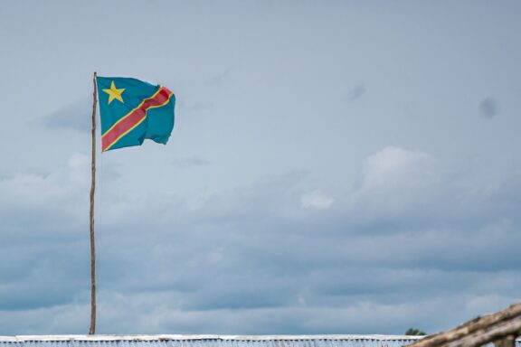 Flag of the Democratic Republic of the Congo fluttering against a cloudy sky.